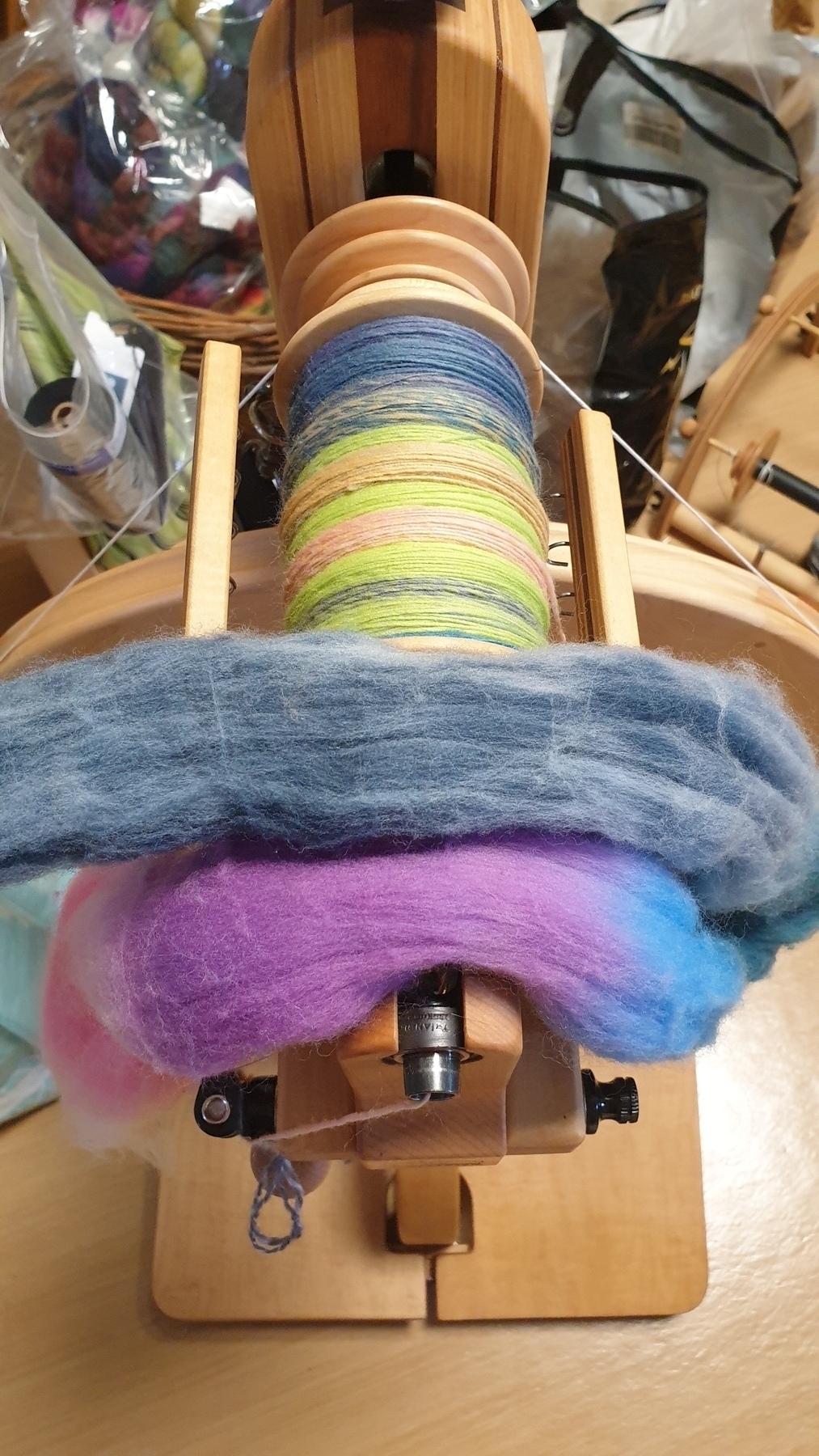 An almost full bobbin of spun yarn on a spinning wheel.